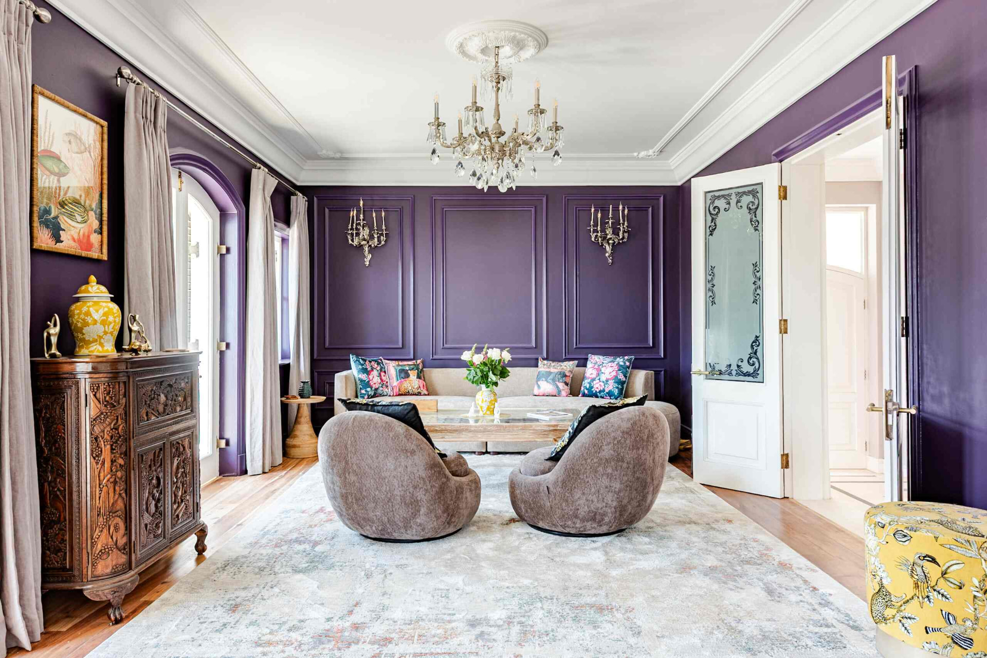 Panelled lounge in deep purple with chandelier, carved cabinet and pale rug